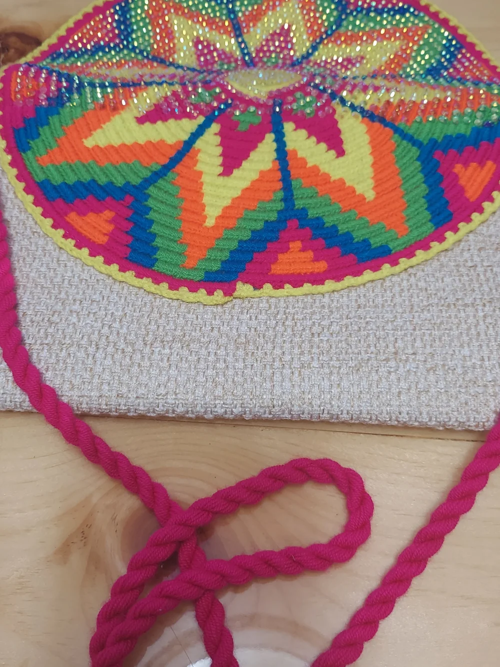 Handmade Wayuu-style jute clutch featuring a vibrant, multicolored beaded floral